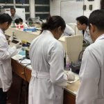 students work in lab in white coats